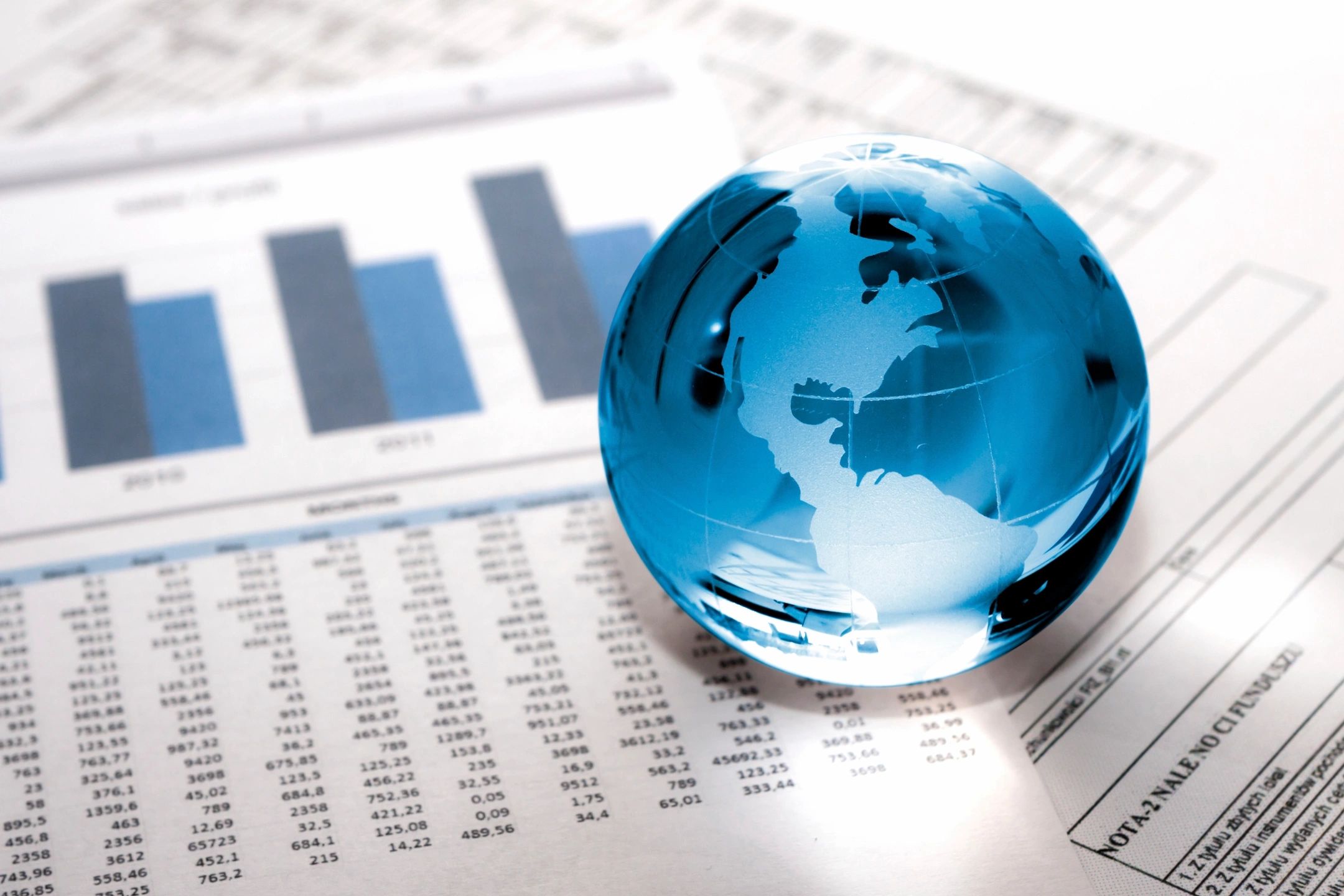 A glass globe resting on financial graphs and charts.