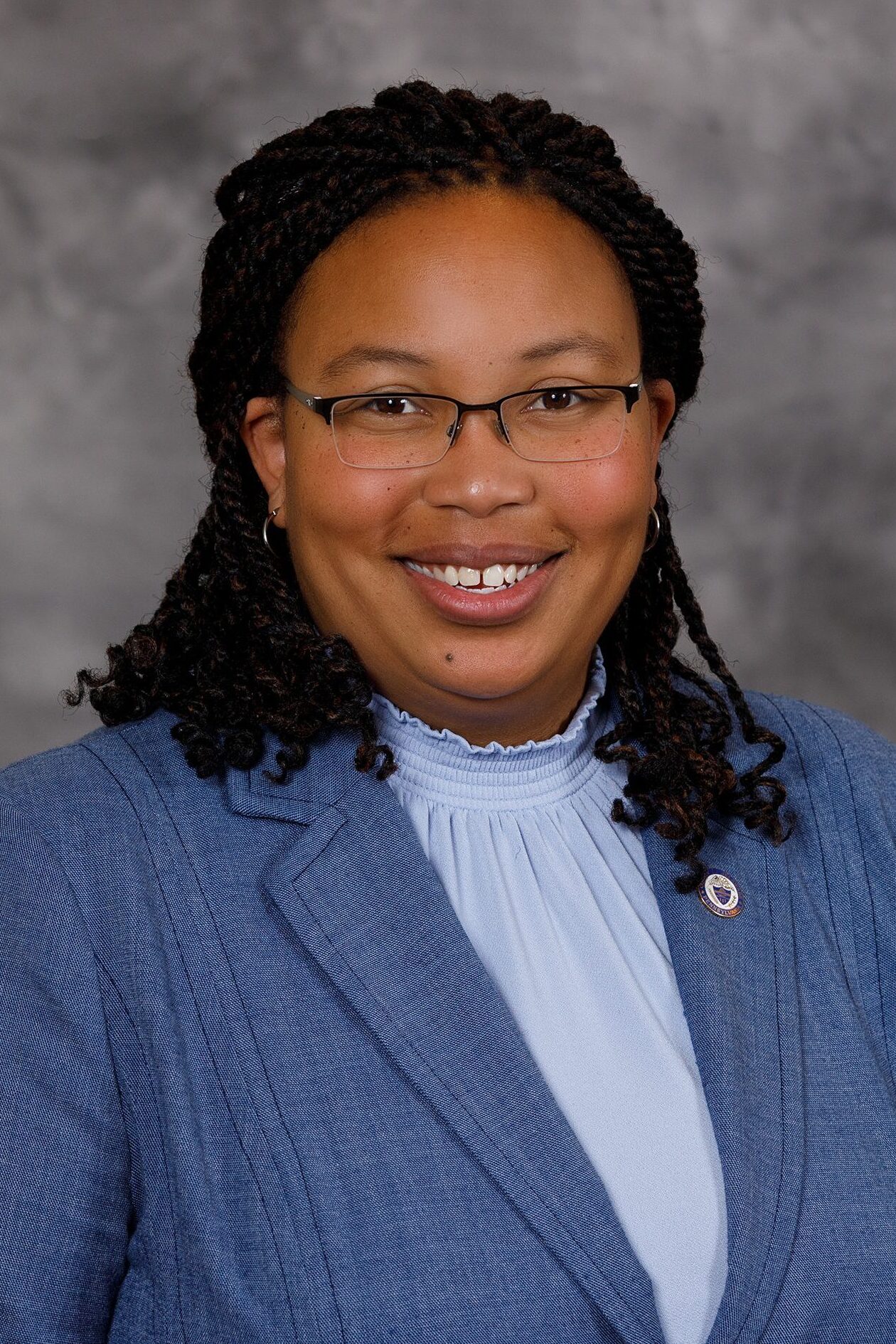 Professional woman smiling, wearing glasses and a blue blazer.