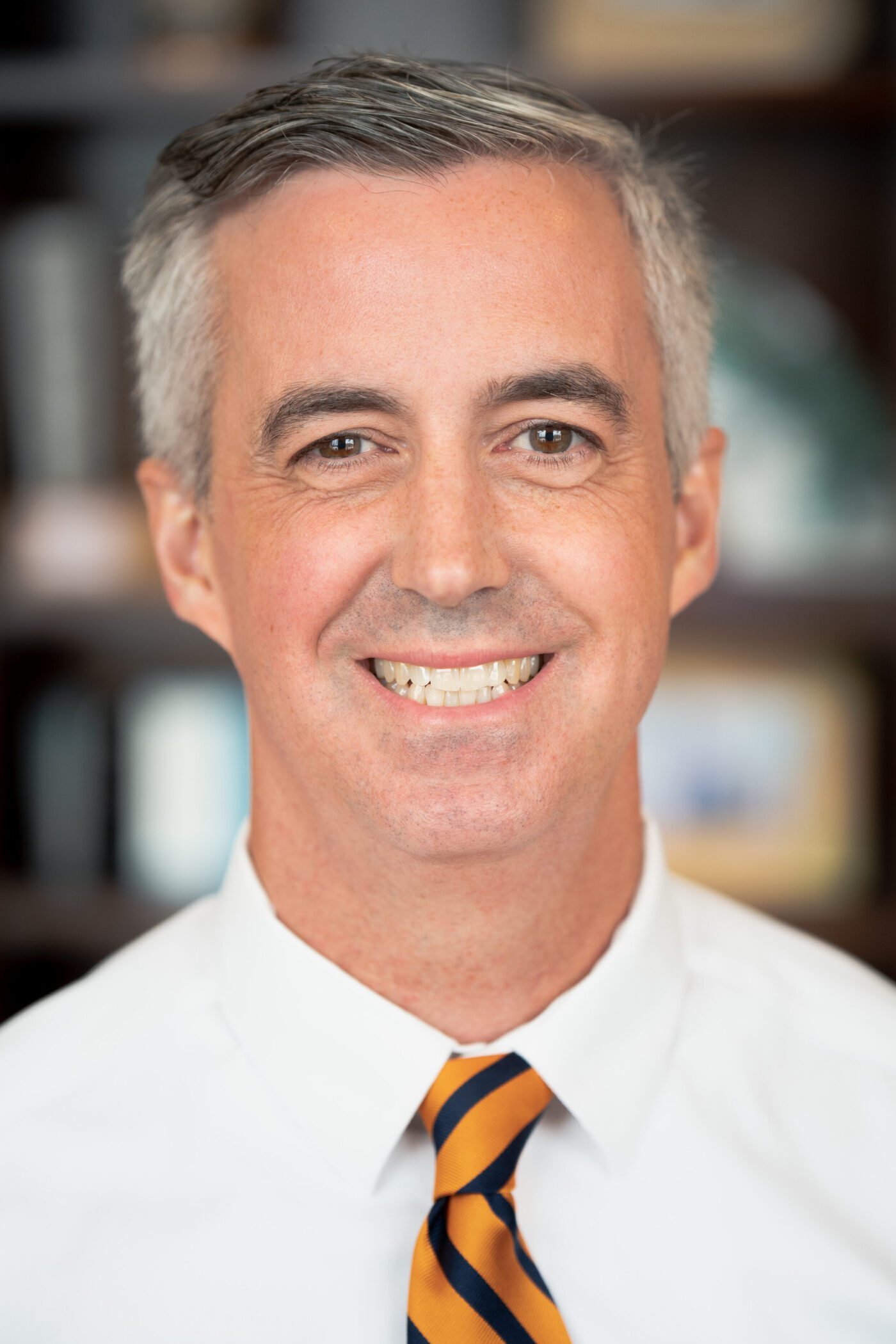 Smiling middle-aged man in a white shirt and striped tie.